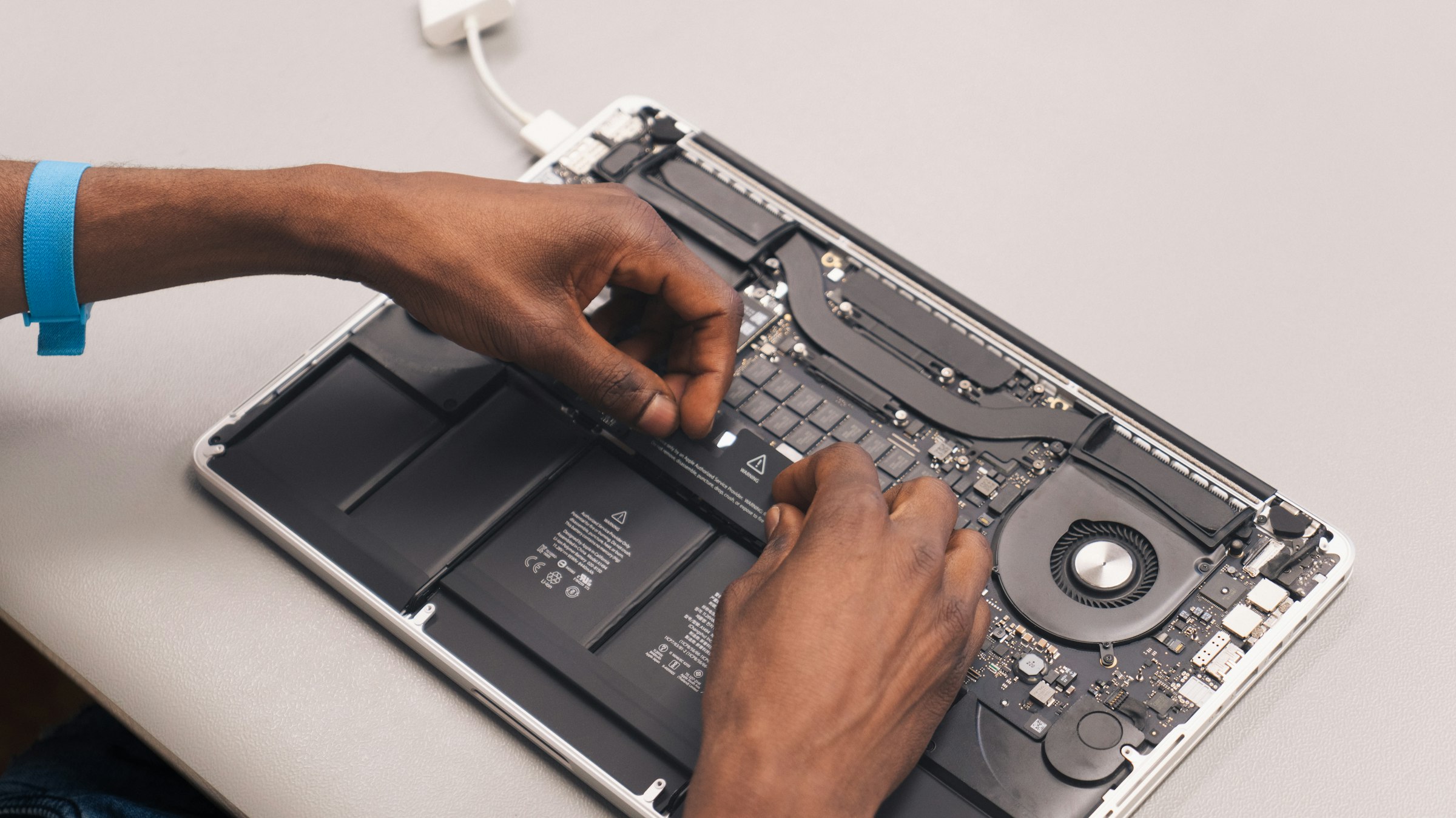 A technician's hands working inside an open MacBook Pro